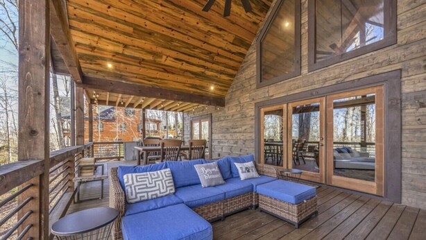 A covered outdoor seating area with a wooden deck, wicker furniture, and a view of the surrounding landscape. - Blue Ridge Escape | Luxury Mtn. Cabin near Lake BR (Blue Ridge)