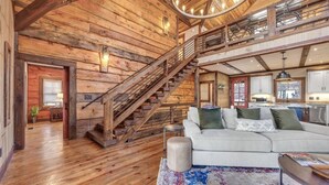 A spacious living area with a staircase, wooden walls, and a modern kitchen. - Blue Ridge Escape | Luxury Mtn. Cabin near Lake BR (Blue Ridge)