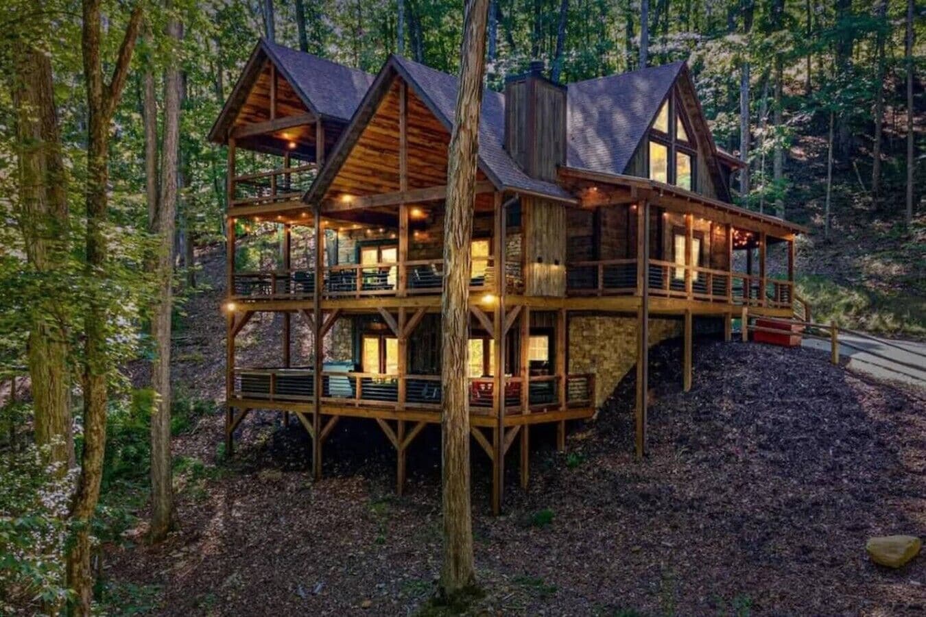 A multi-level wooden cabin with balconies, surrounded by a forest.