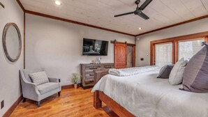 A bedroom with a bed, a chair, a TV, a dresser, and a ceiling fan. - Blue Ridge Escape | Luxury Mtn. Cabin near Lake BR (Blue Ridge)