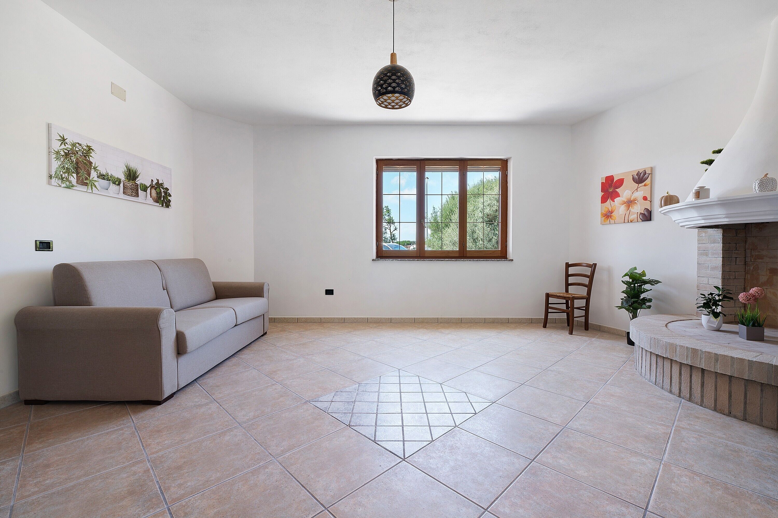 Un salon spacieux avec un canapé, un fauteuil, une cheminée et une grande fenêtre.