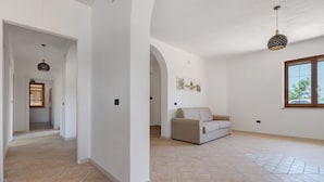 Ein geräumiges Zimmer mit einem beigefarbenen Sofa, einem Esstisch und einem Fenster mit Blick.