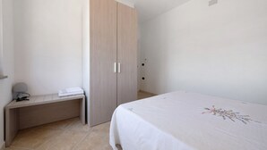 Ein Schlafzimmer mit Bett, Schrank, Nachttisch und Lampe.