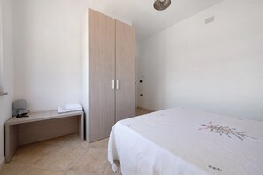 A bedroom with a bed, a wardrobe, a bedside table, and a lamp.