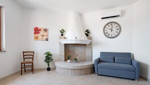 Ein Wohnzimmer mit Kamin, einer Couch, einem Sessel und einer Wanduhr.
