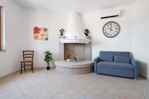 A living room with a fireplace, a sofa, a chair, and a clock on the wall.