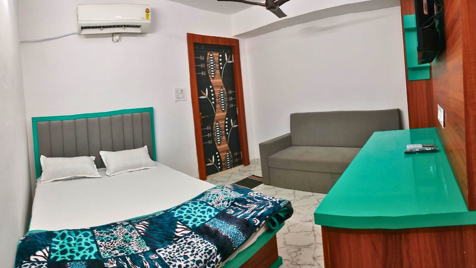 Ein Hotelzimmer mit Bett, einer Sitzecke, einem Schreibtisch und einem Fernseher.