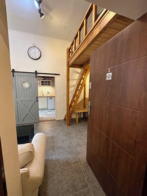 Ein Zimmer mit einer Holztreppe, einer weißen Tür mit einer Nummer und einer Uhr an der Wand.
