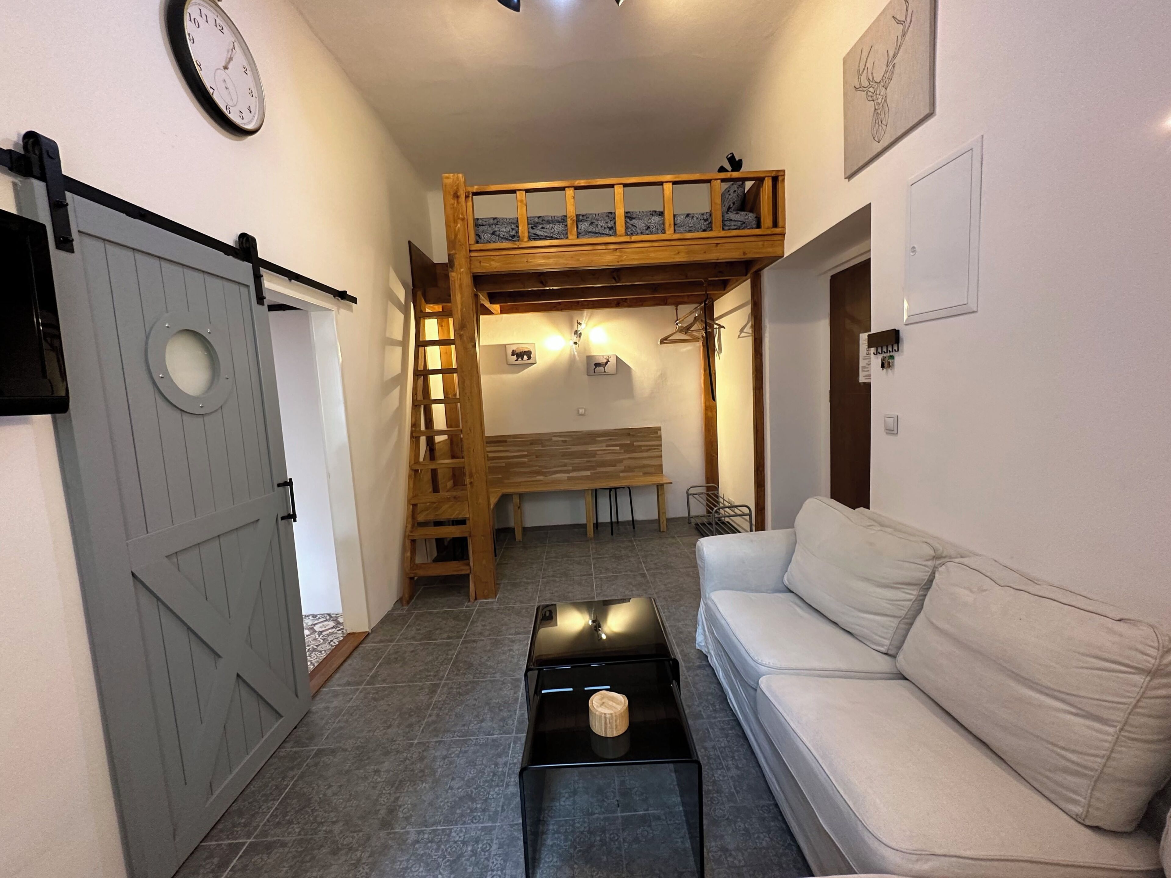 Une pièce comprenant un lit superposé, un canapé, une table basse et une porte dotée d’une fenêtre ronde.