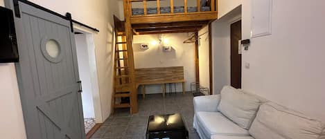 A room with a bunk bed, a sofa, a coffee table, and a door with a circular window.