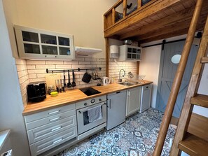 Eine kleine Küche mit einer Holzausstattung, einem eingebauten Backofen und einem Spülbecken.
