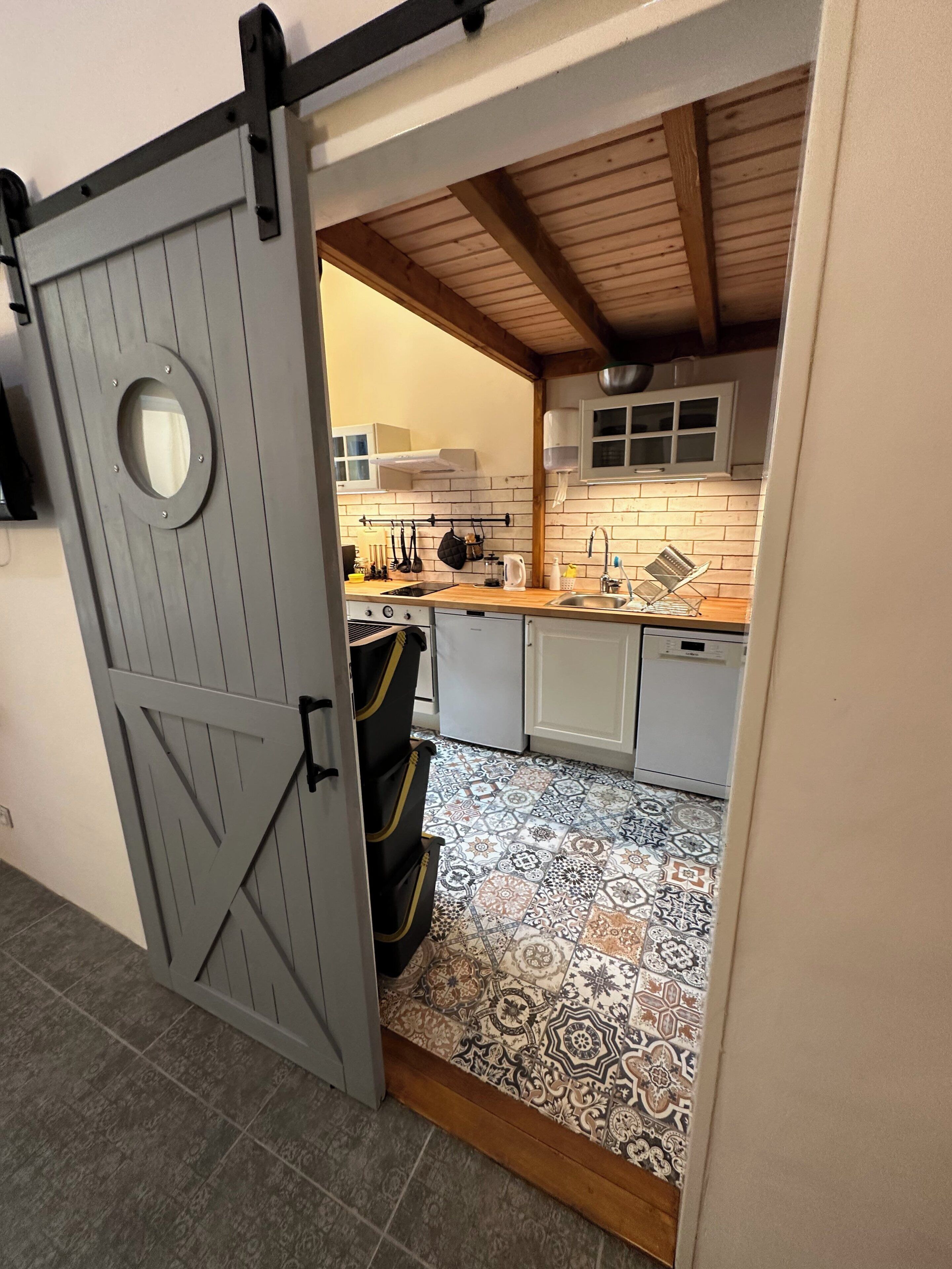 A kitchen with a patterned floor, a sliding barn door, and a view into the adjacent room.
