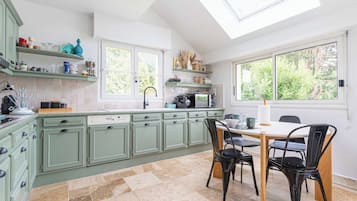 A kitchen with green cabinets, a dining table with chairs, and a large window.
