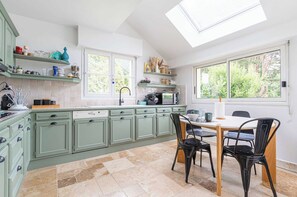 A kitchen with green cabinets, a dining table with chairs, and a large window. - Exceptional House With Pool 12P - Englesqueville (Englesqueville-en-Auge)