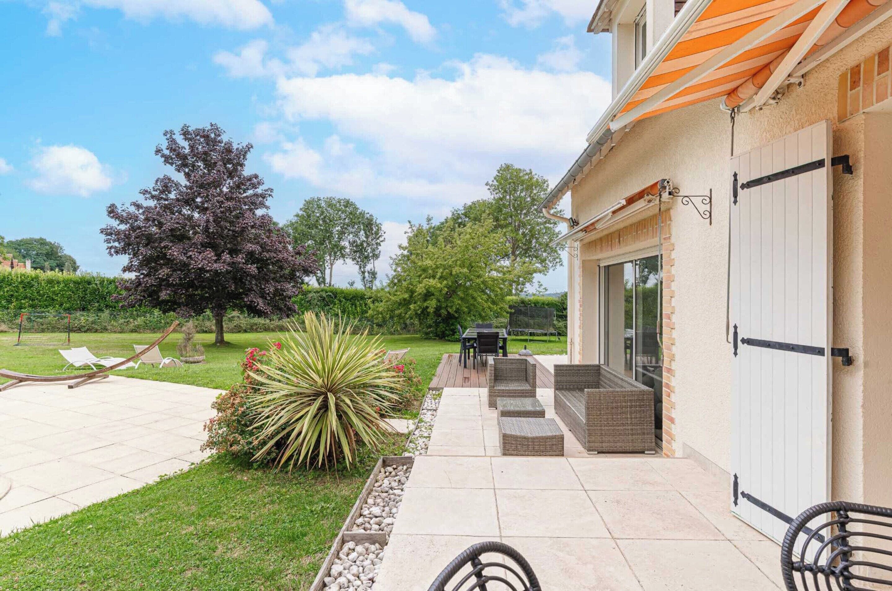 Une terrasse avec des meubles d’extérieur, un grand arbre et un bâtiment doté d’une porte de garage.