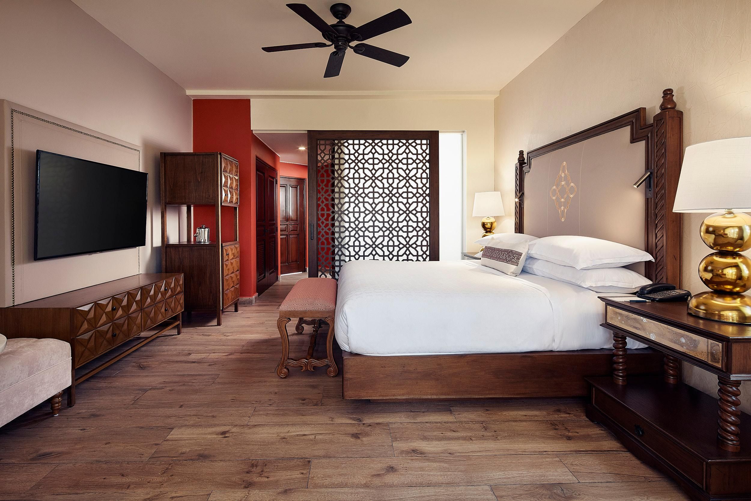 Une chambre d’hôtel avec un grand lit, une télévision, un bureau avec une lampe et un plancher en bois.