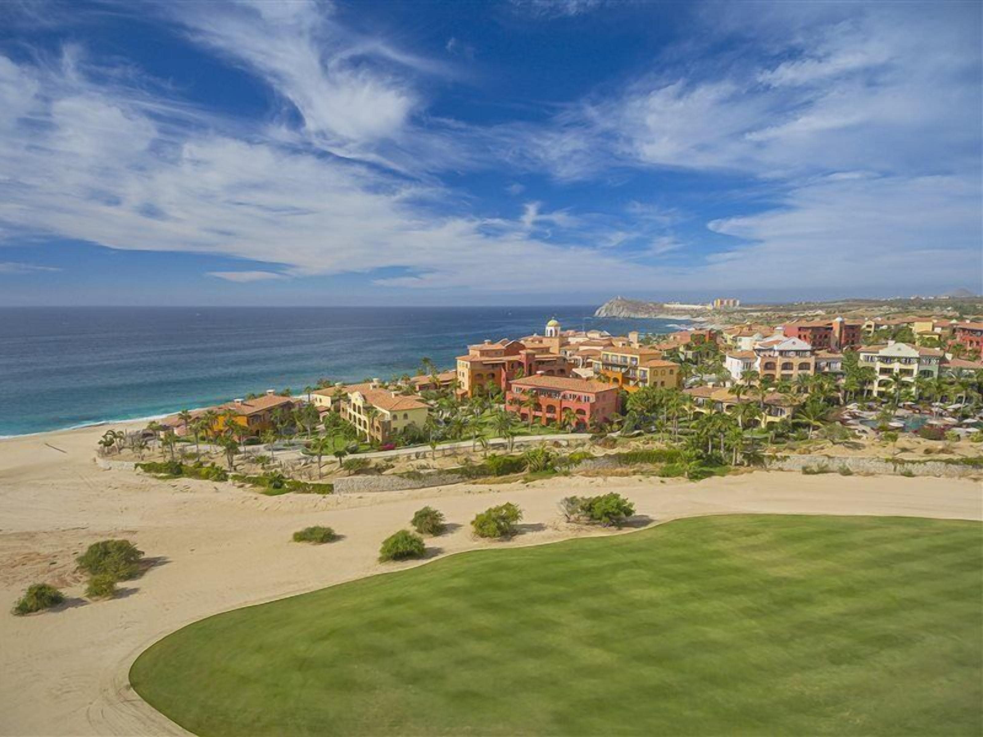 A coastal resort with a beach, a golf course, and a cluster of buildings.