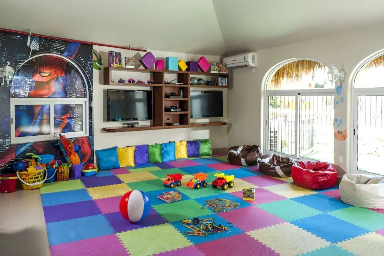 A playroom with colorful foam mats, toys, and a Spiderman poster.