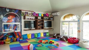 Een speelkamer met kleurrijke foammatten, speelgoed en een Spiderman poster.