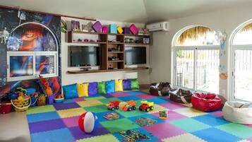 Une salle de jeux avec des tapis en mousse colorés, des jouets et une affiche de Spiderman.