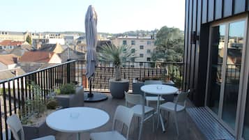Une terrasse extérieure avec des tables et des chaises, un pot de fleurs et une vue sur le paysage urbain.
