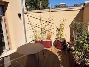 A patio with a table and chairs, potted plants, and a bamboo trellis.