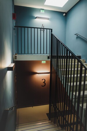 A staircase with a metal railing, an exit sign, and a door marked with the number 3.