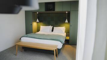 A modern bedroom with a bed, bedside lamps, and a bench.