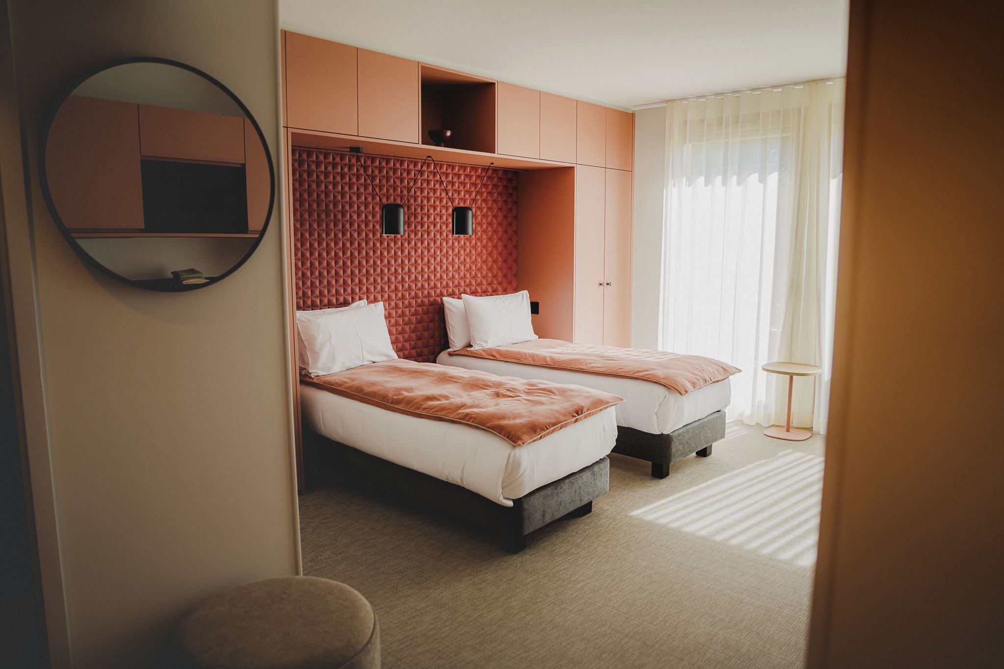 A hotel room with two beds, a large mirror, and a small round table.