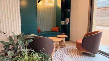 A cozy seating area with a neon sign, a bookshelf, and a window view.