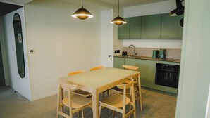 Une cuisine compacte avec un coin repas, comprenant une table avec des chaises, une machine à café et un lave-vaisselle.