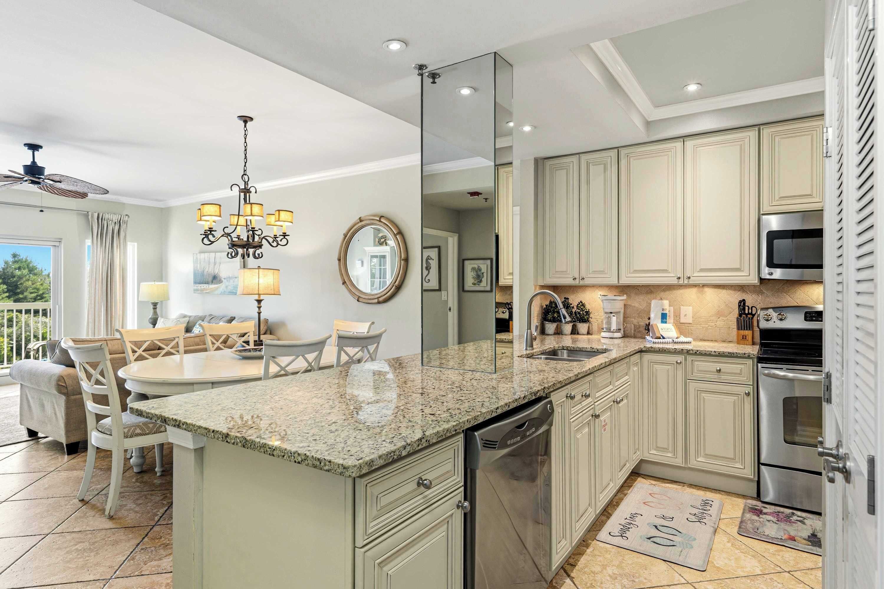 A modern kitchen with granite countertops, stainless steel appliances, and light-colored cabinetry.