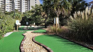 A miniature golf course with a gravel path, green artificial turf, and a palm tree. - Coastal Comfort at TOPSL Summit 309C (Miramar Beach)