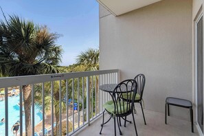 A balcony with a view of a swimming pool, two chairs, and a small table. - Coastal Comfort at TOPSL Summit 309C (Miramar Beach)