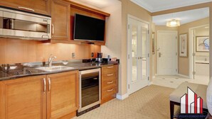 A kitchen with wooden cabinets, stainless steel appliances, a built-in oven, and a flat-screen TV. - MGM Signature-08-704 Jacuzzi Studio (Las Vegas)