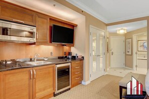 A kitchen with wooden cabinets, stainless steel appliances, a built-in oven, and a flat-screen TV. - MGM Signature-08-704 Jacuzzi Studio (Las Vegas)