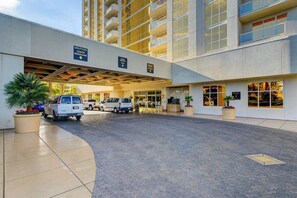 A hotel entrance with a covered driveway, multiple vehicles, and a sign for shuttle services. - MGM Signature-09-704 Jacuzzi Studio (Las Vegas)