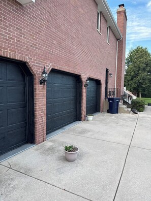 Un bâtiment en briques avec deux portes de garage et une petite plante en pot sur le trottoir.
