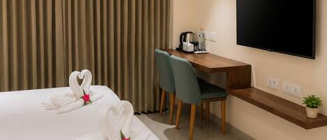 Una habitación de hotel con una cama, un escritorio, un televisor y una ventana con cortinas.