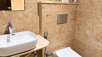 Un baño con un lavamanos blanco, inodoro y zona de ducha.