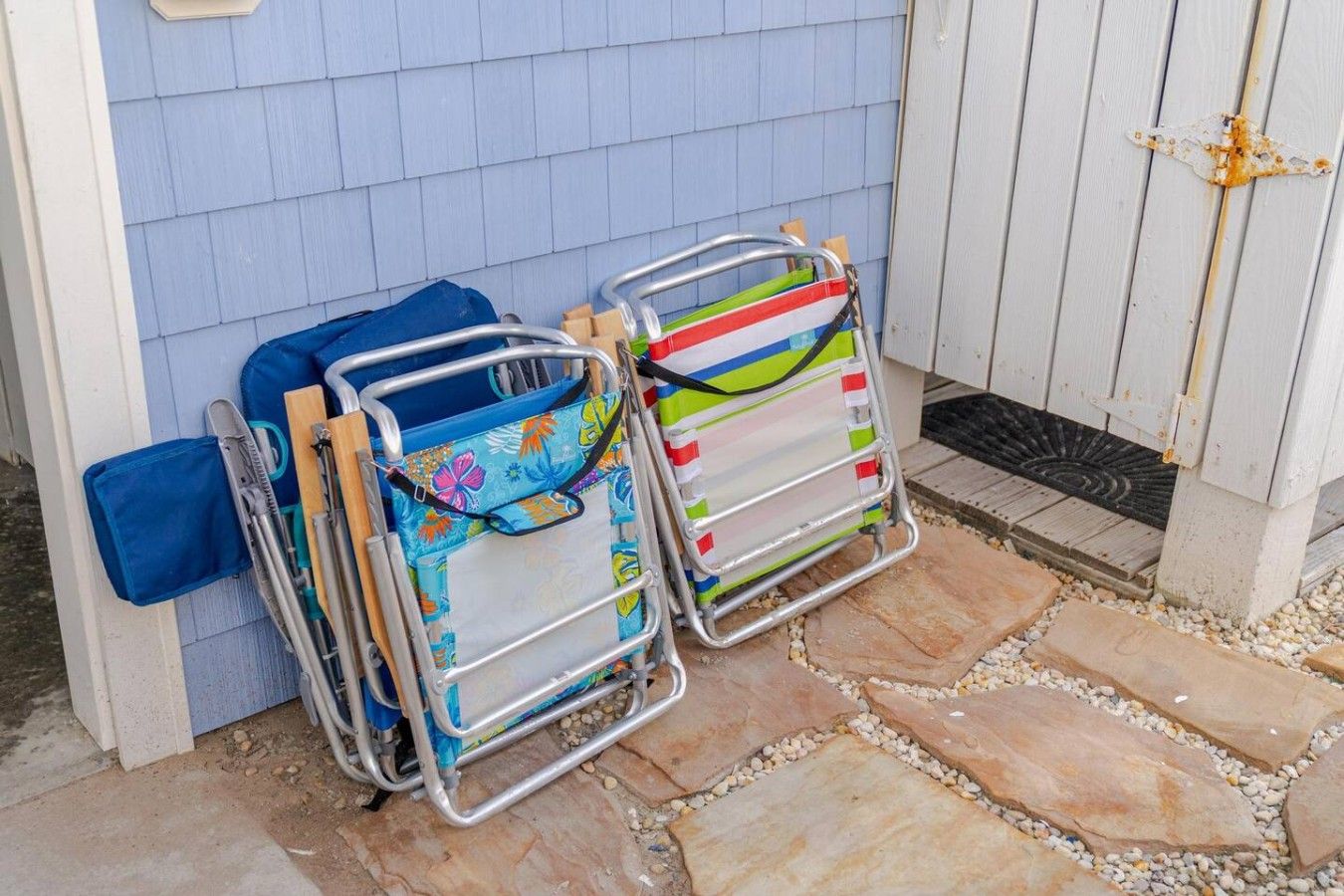 Deux chaises pliantes aux motifs colorés, un sac bleu et une porte en bois avec une poignée en métal.