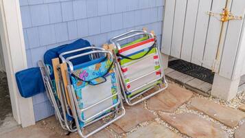 Two folding chairs with colorful patterns, a blue bag, and a wooden door with a metal handle.