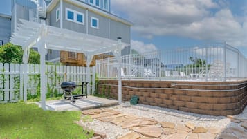 A residential property with a patio, a barbecue grill, a white fence, and a brick wall.