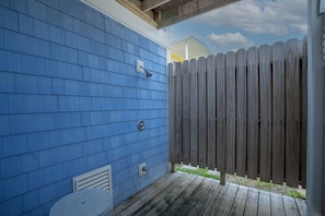 A blue exterior wall with a wooden deck and a white fence.