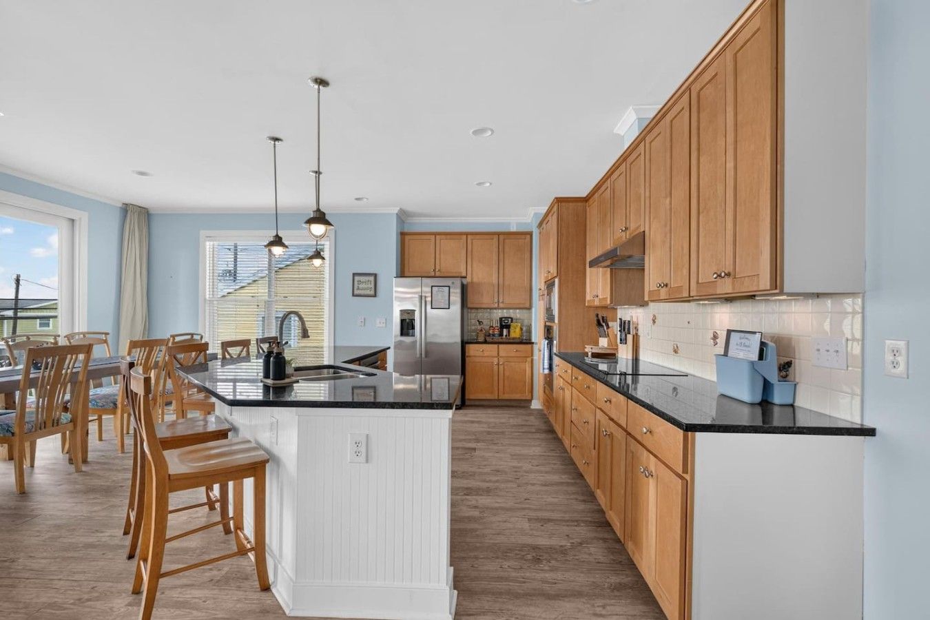 Une cuisine moderne avec des meubles en bois, un îlot central et des luminaires suspendus.