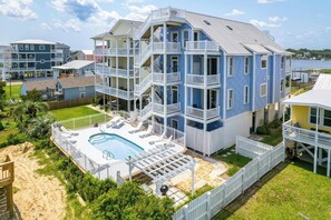 A multi-story building with a pool, multiple balconies, and a waterfront view.