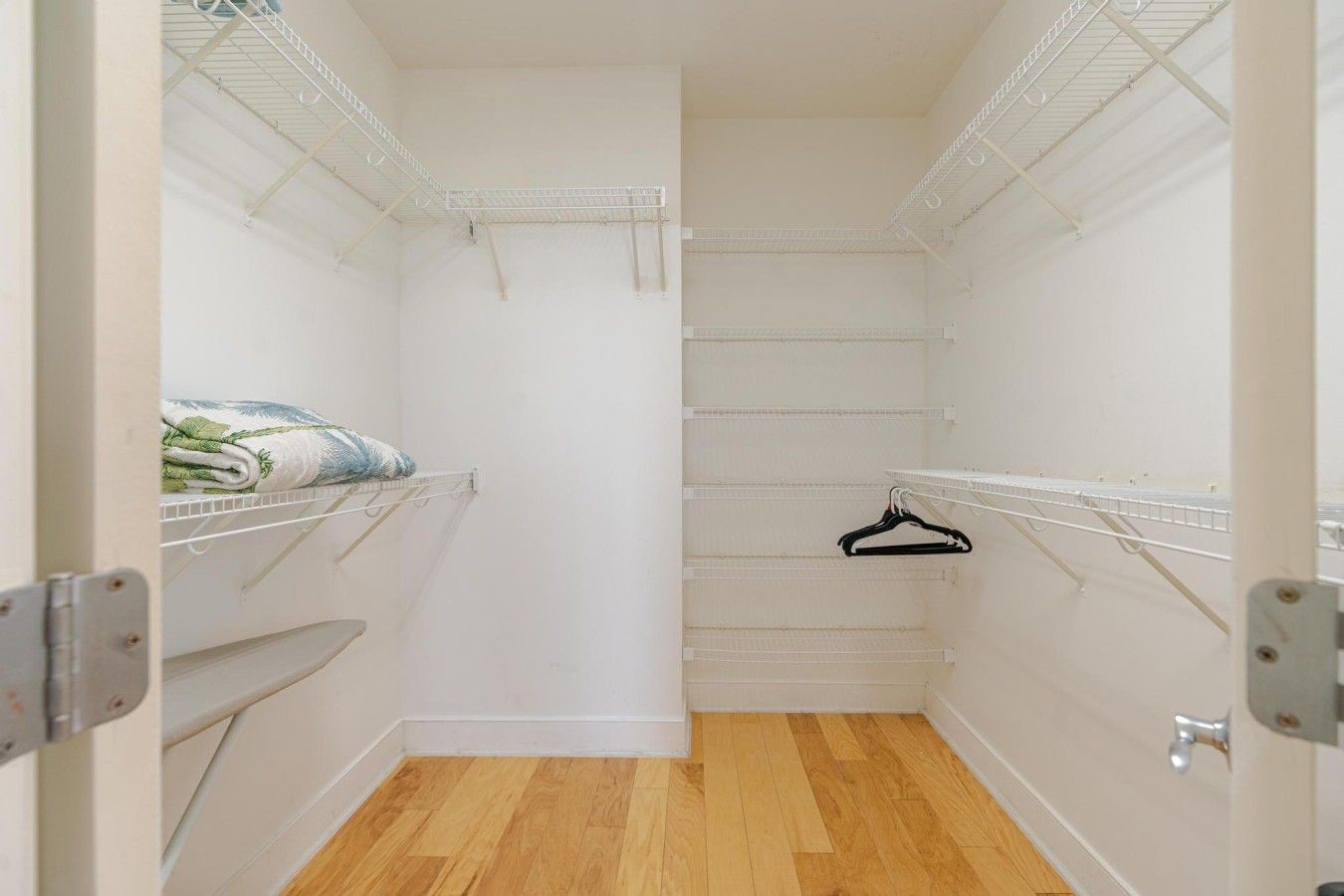 Un vestidor estrecho con paredes blancas y suelo de madera.