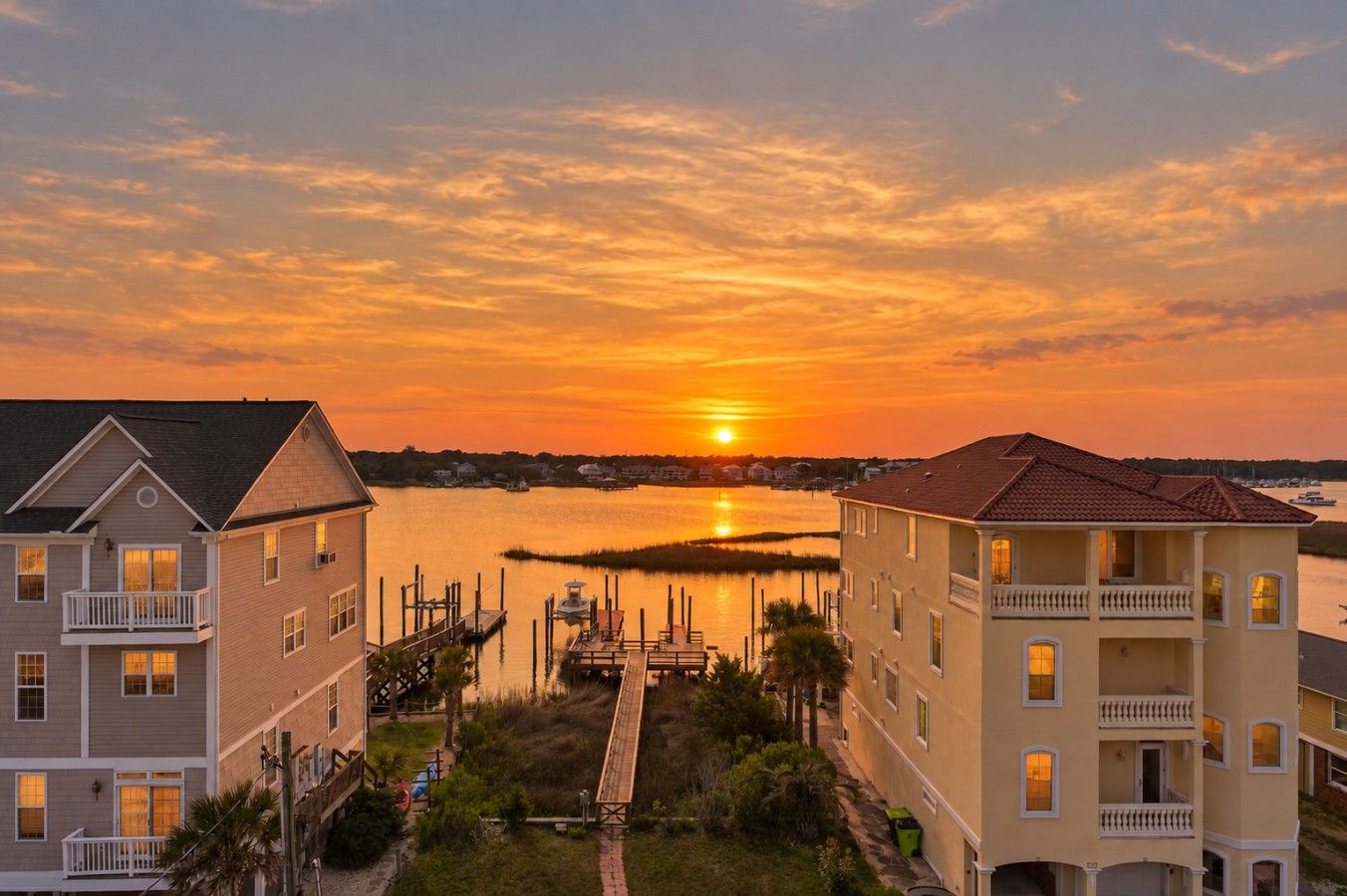 A waterfront property with a dock, a pier, and a sunset view.