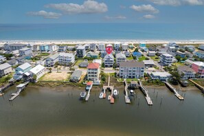 A coastal residential area with houses, a marina, and a beach in the background.