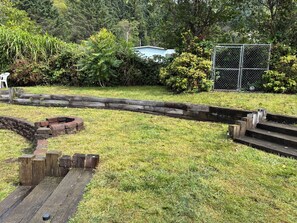 Ein grasbewachsenes Gelände mit einer Steinmauer, Holzstufen und einem Drahtzaun.